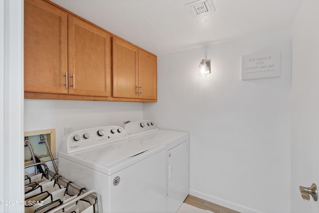 laundry room featuring washing machine and dryer, cabinet space, baseboards, and visible vents