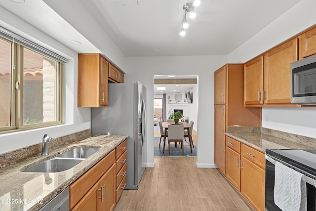 kitchen with light stone counters, plenty of natural light, stainless steel appliances, and a sink