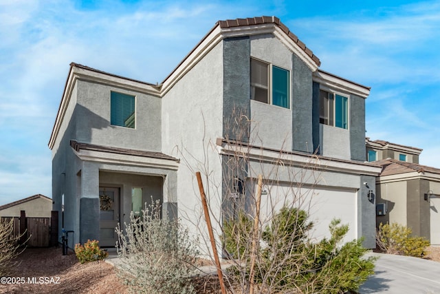 view of front facade with a tiled roof, fence, and stucco siding