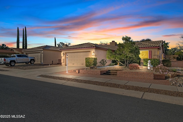 view of front of house with driveway, a tile roof, a chimney, an attached garage, and stucco siding