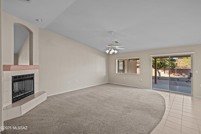 unfurnished living room with light carpet, light tile patterned floors, a tile fireplace, lofted ceiling, and ceiling fan