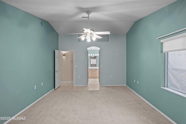 empty room featuring carpet floors, baseboards, vaulted ceiling, and a ceiling fan