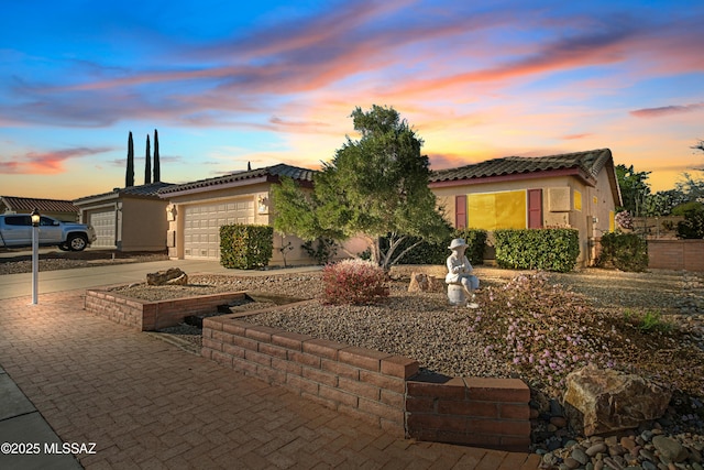 view of front facade with driveway, an attached garage, a tile roof, and stucco siding