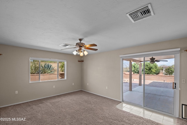 spare room featuring plenty of natural light, visible vents, and light colored carpet