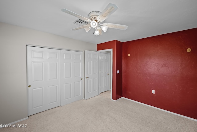 unfurnished bedroom featuring baseboards, visible vents, a ceiling fan, carpet, and a closet