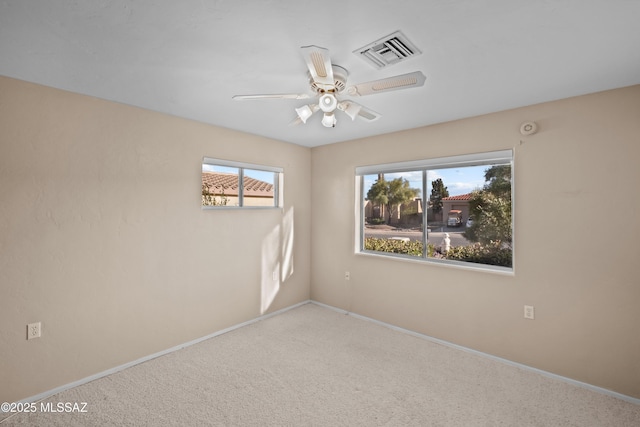 carpeted spare room featuring visible vents, ceiling fan, and baseboards