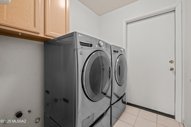 laundry area featuring light tile patterned floors, cabinet space, and separate washer and dryer