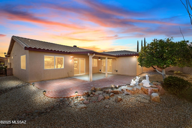 back of house featuring a tile roof, a patio, stucco siding, a ceiling fan, and fence