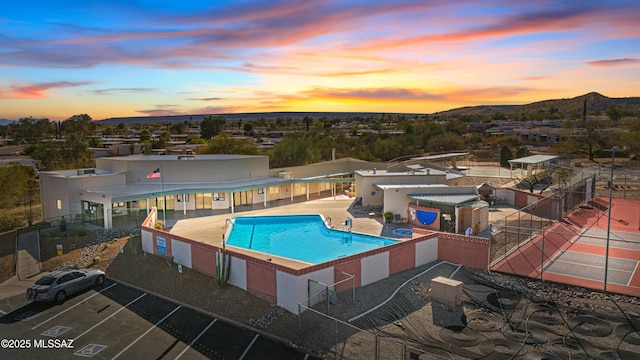 community pool featuring a patio area, a mountain view, and fence