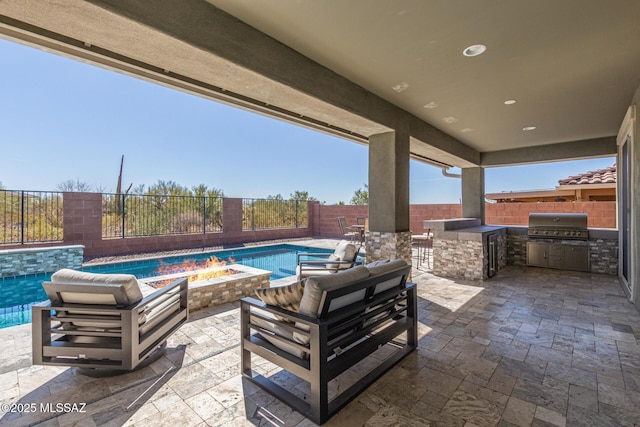 view of patio with area for grilling, outdoor dry bar, a fenced backyard, a fire pit, and exterior kitchen