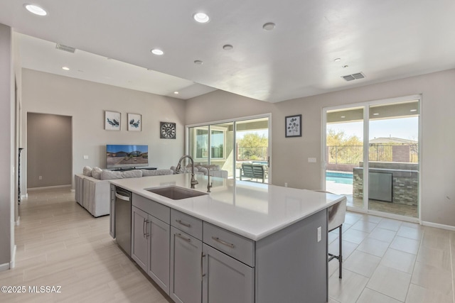 kitchen with visible vents, gray cabinets, a sink, stainless steel dishwasher, and a wealth of natural light