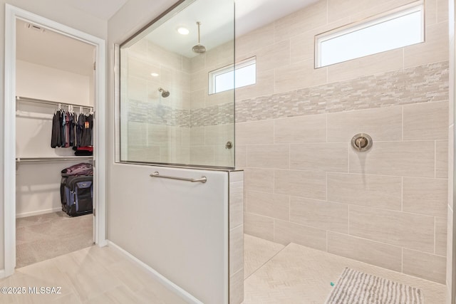 full bath featuring baseboards, a spacious closet, and a walk in shower