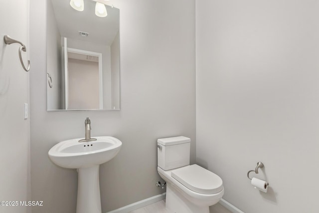 half bath featuring toilet and baseboards