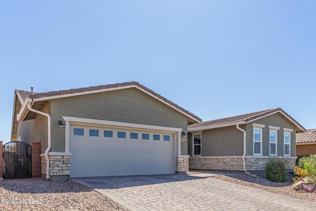 ranch-style home with decorative driveway, stone siding, an attached garage, and stucco siding