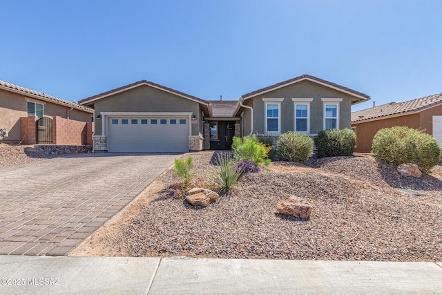 ranch-style house featuring decorative driveway, a gate, an attached garage, and stucco siding