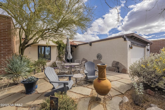 view of patio / terrace with a garage and outdoor dining area