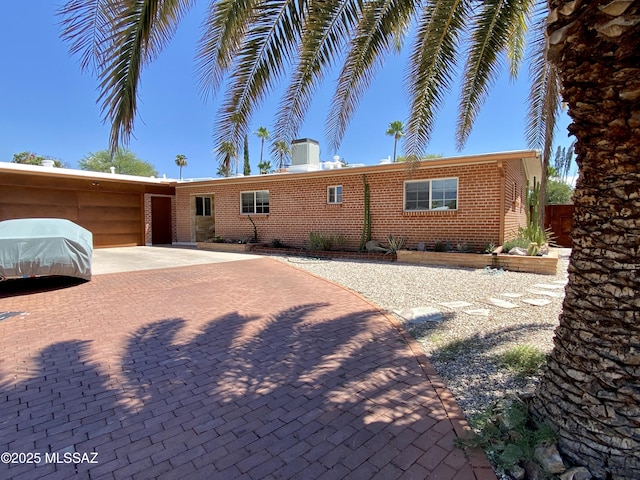 ranch-style home featuring brick siding and decorative driveway