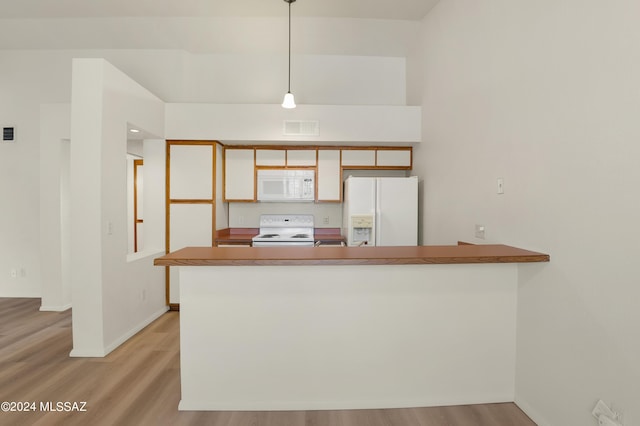 kitchen featuring light wood finished floors, visible vents, white appliances, a peninsula, and baseboards