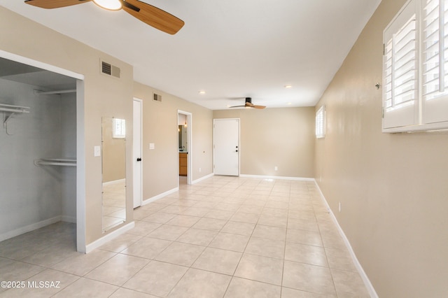 spare room featuring light tile patterned floors, baseboards, visible vents, and a ceiling fan