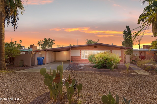 mid-century modern home with a carport, brick siding, and driveway