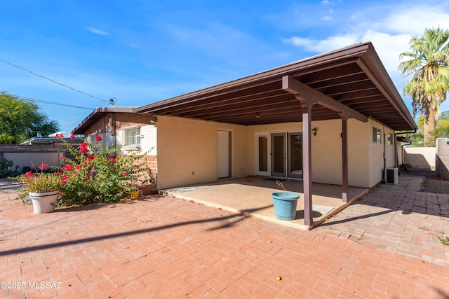 back of property featuring french doors, stucco siding, fence, and a patio