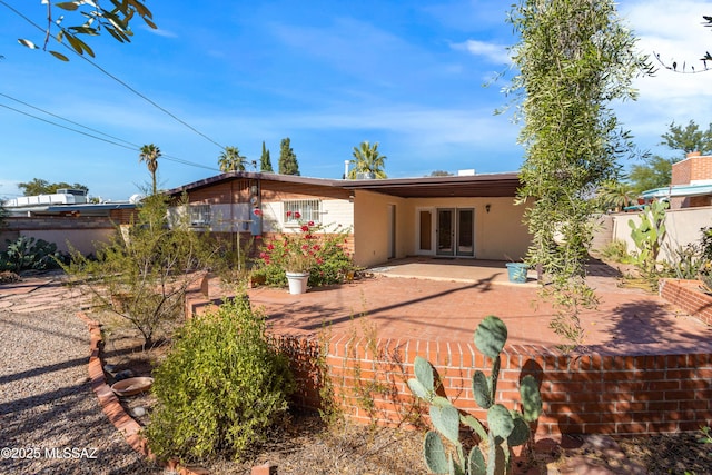 rear view of house featuring a patio, french doors, fence, and stucco siding