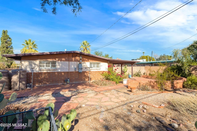 rear view of house featuring a patio area, fence, and brick siding