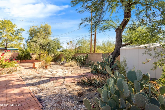 view of yard featuring a fenced backyard, an outdoor structure, a storage shed, and a patio