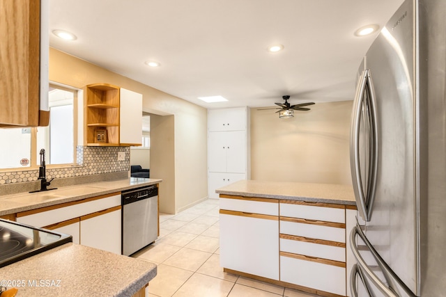 kitchen with stainless steel appliances, a sink, white cabinets, backsplash, and open shelves