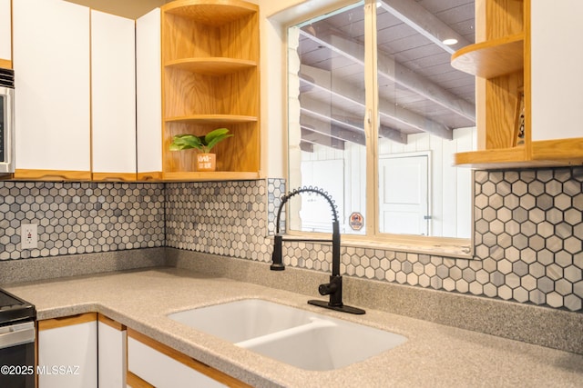 kitchen with open shelves, a sink, and white cabinets