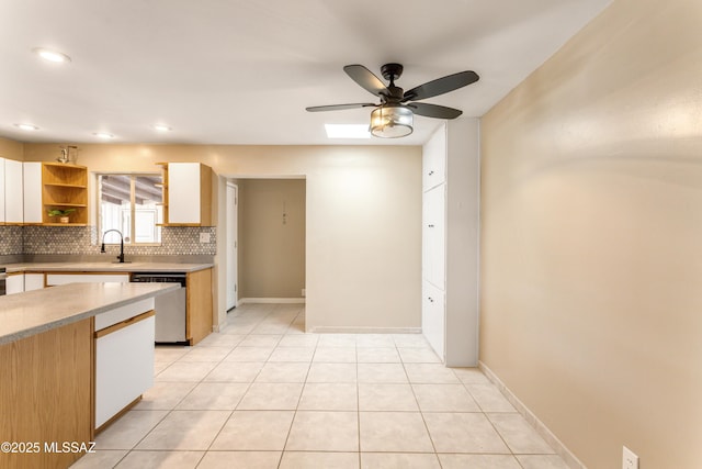 kitchen with light tile patterned floors, light countertops, stainless steel dishwasher, backsplash, and open shelves