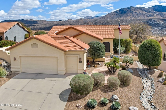 mediterranean / spanish-style home with a mountain view, stucco siding, an attached garage, and a tile roof