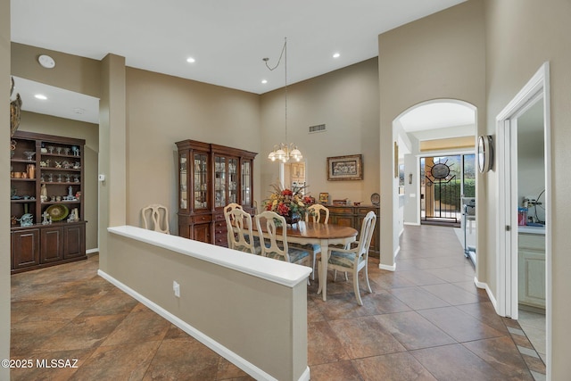 dining area featuring visible vents, arched walkways, a high ceiling, baseboards, and a chandelier