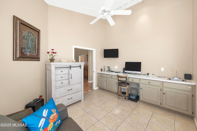 home office with a sink, a high ceiling, light tile patterned flooring, and a ceiling fan