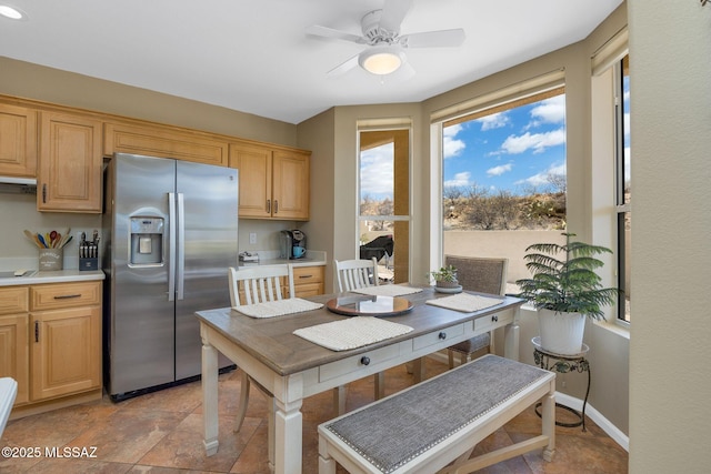 kitchen with light brown cabinetry, stainless steel fridge with ice dispenser, light countertops, baseboards, and ceiling fan