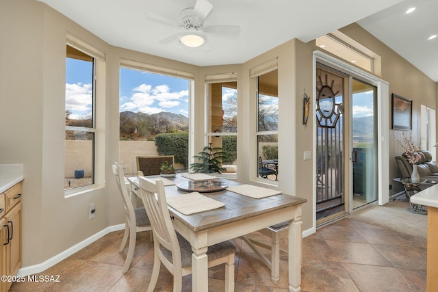 dining area featuring a ceiling fan, light tile patterned floors, baseboards, and a mountain view