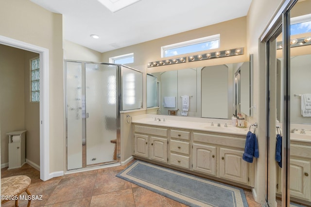 bathroom with double vanity, baseboards, a stall shower, and a sink