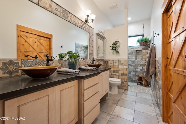 full bathroom with double vanity, tile walls, wainscoting, a walk in shower, and a sink