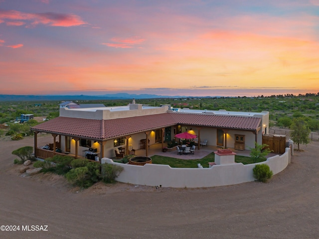 rear view of house with driveway, a fire pit, a patio, a tile roof, and fence