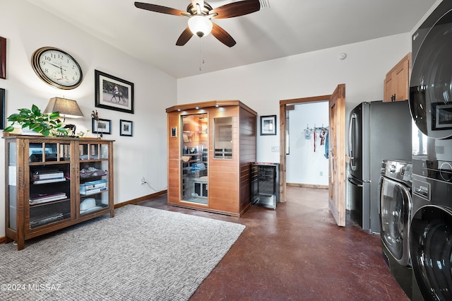 interior space featuring stacked washer and clothes dryer, freestanding refrigerator, ceiling fan, concrete flooring, and baseboards