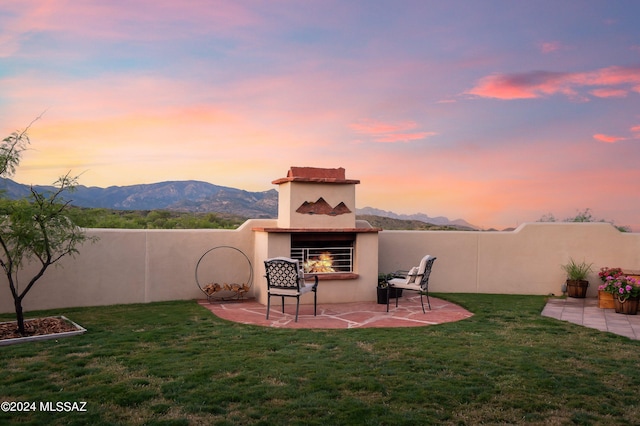 view of yard featuring a lit fireplace, a patio area, fence, and a mountain view