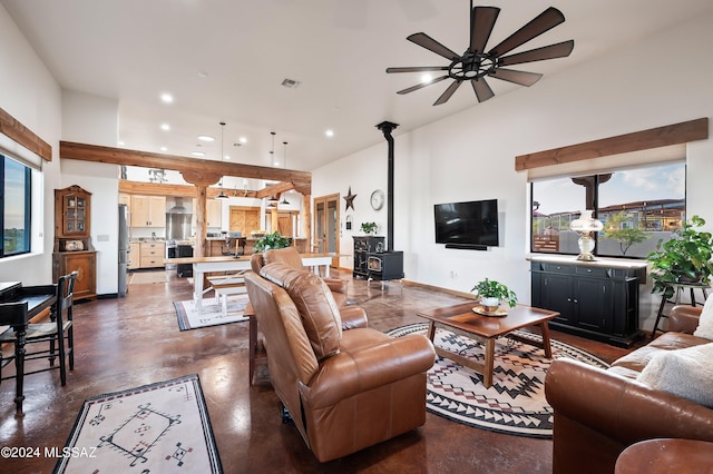 living room with finished concrete flooring, visible vents, a wood stove, and a healthy amount of sunlight