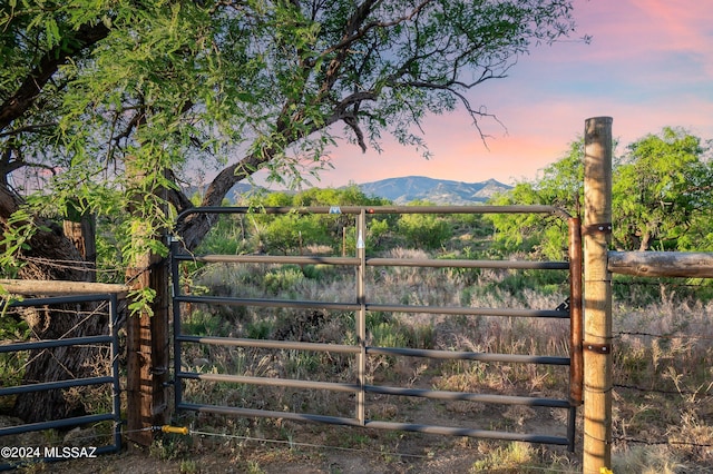 gate at dusk with a mountain view and fence