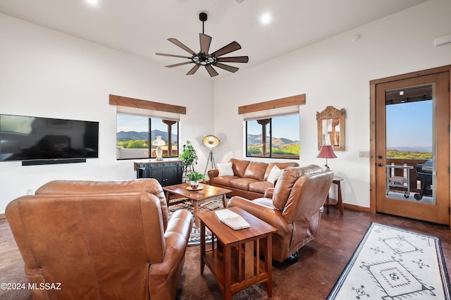 living room with concrete flooring, ceiling fan, a wealth of natural light, and baseboards