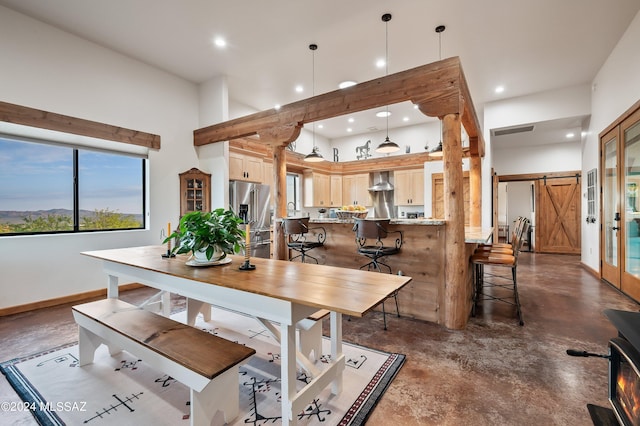 dining room with finished concrete flooring, recessed lighting, a high ceiling, a barn door, and baseboards