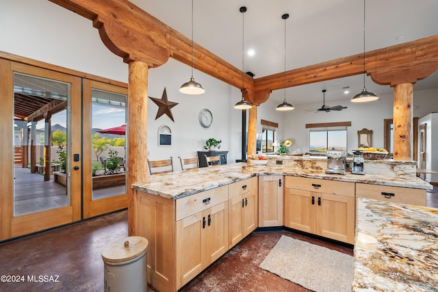 kitchen with hanging light fixtures, light stone countertops, light brown cabinets, and french doors