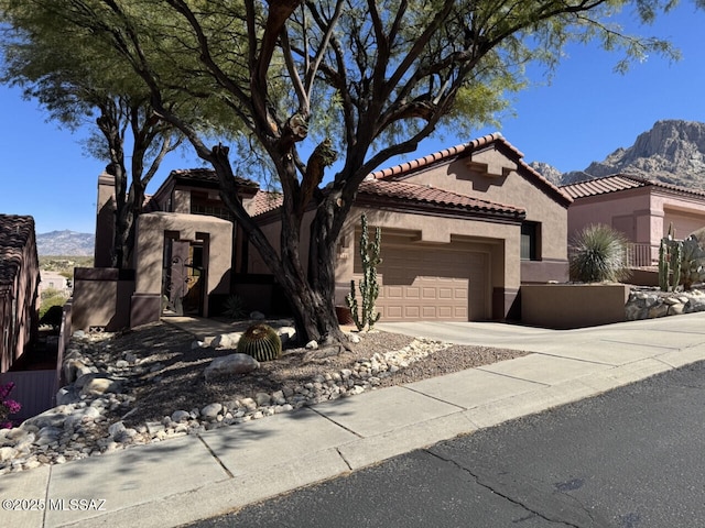 view of front of home with concrete driveway, an attached garage, a mountain view, and stucco siding