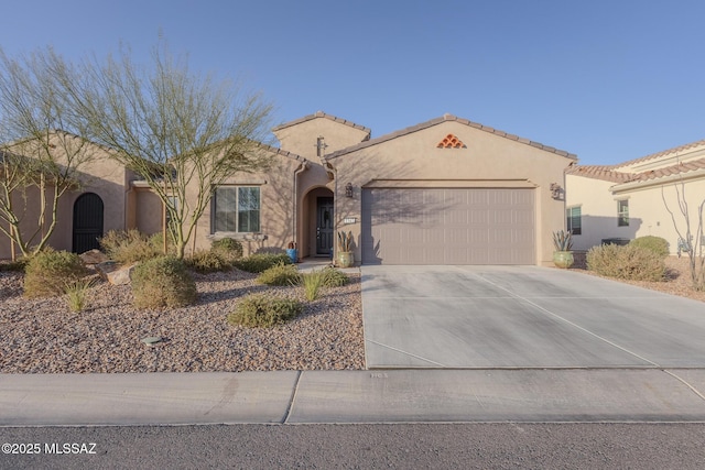 mediterranean / spanish house with concrete driveway, an attached garage, a tile roof, and stucco siding