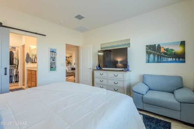 bedroom with visible vents, a spacious closet, and a barn door