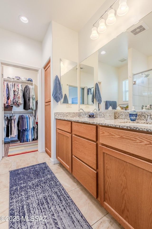 full bath with tile patterned flooring, vanity, visible vents, a spacious closet, and a stall shower